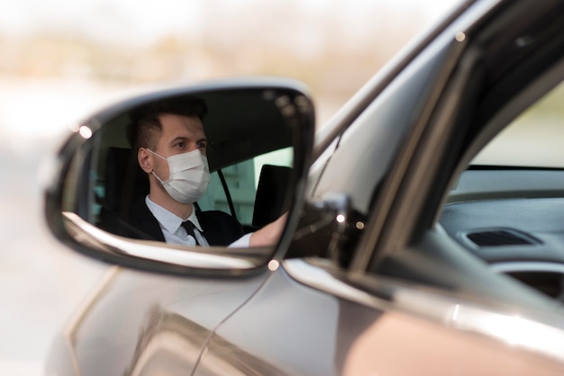 Hombre en espejo de coche con máscara