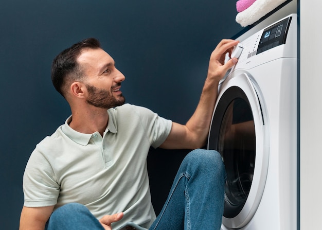 Hombre esperando que la lavadora termine su programa