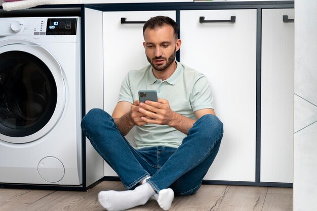 Hombre esperando que la lavadora termine su programa