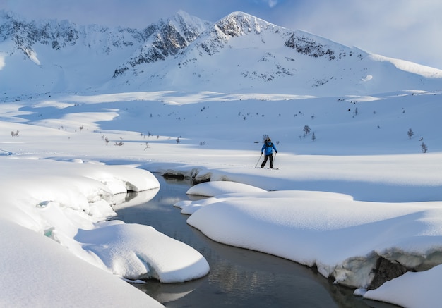 Hombre esquiando en las montañas cubiertas de nieve durante el día