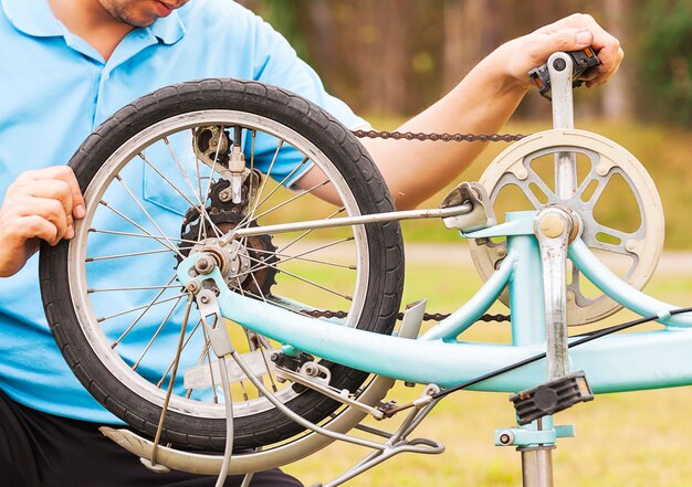 El hombre está arreglando la bicicleta. La foto está enfocada a una rueda.