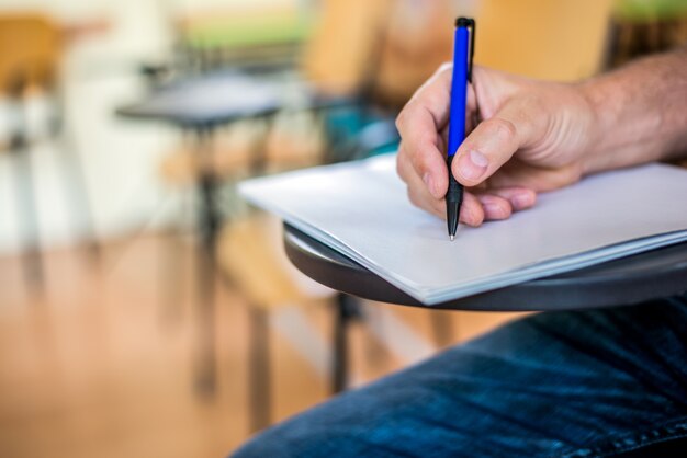 Un hombre está escribiendo / firmando en un papel. Centrado en una mano con la pluma