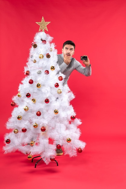 Un hombre está de pie junto al árbol de Navidad.