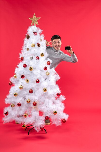 Un hombre está de pie junto al árbol de Navidad.