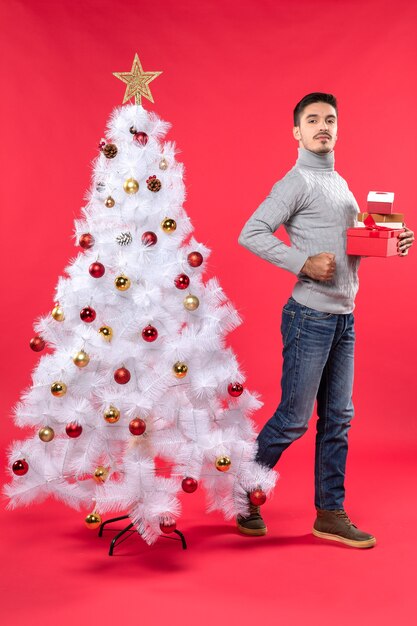 Un hombre está de pie junto al árbol de Navidad.