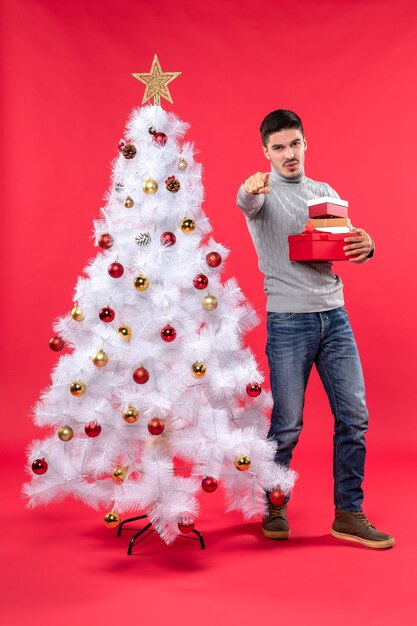 Un hombre está de pie junto al árbol de Navidad.