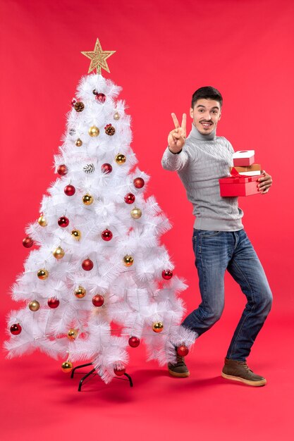 Un hombre está de pie junto al árbol de Navidad.