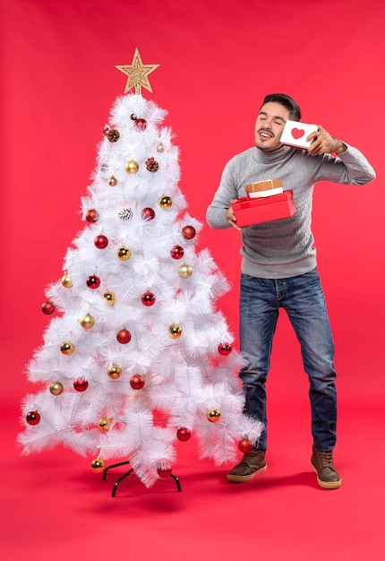 Un hombre está de pie junto al árbol de Navidad.