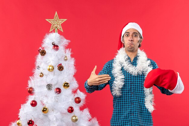 Un hombre está de pie junto al árbol de Navidad.