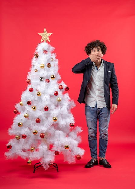 Un hombre está de pie junto al árbol de Navidad.