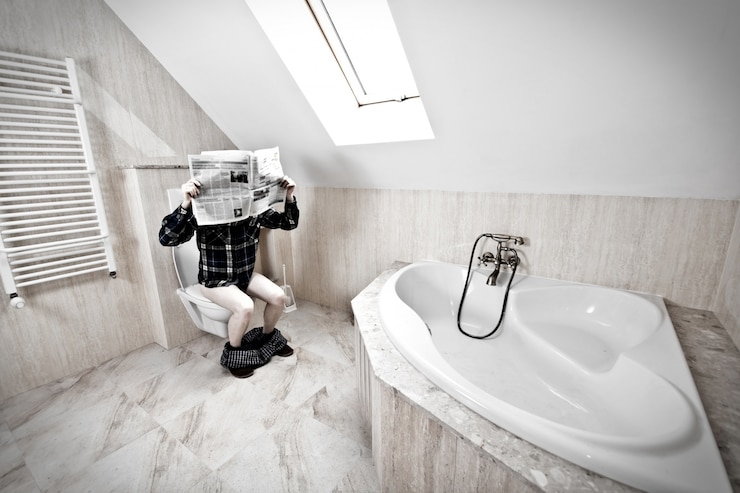 Foto gratuito el hombre está sentado en el inodoro.