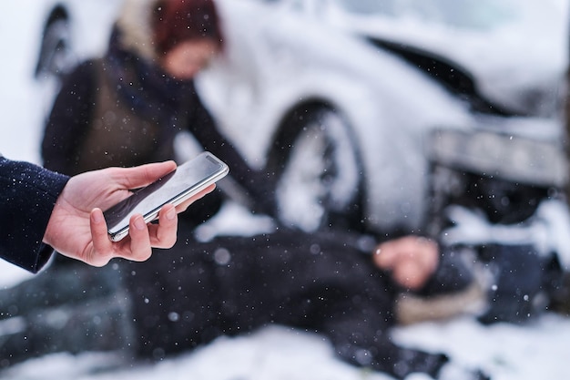 El hombre está tratando de llamar al 112 mientras la mujer está tratando de ayudar a un hombre herido después de un accidente automovilístico.