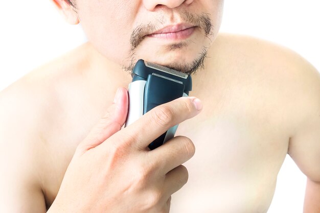 El hombre está utilizando la máquina de afeitar aislada sobre fondo blanco