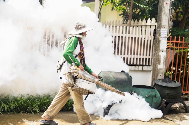 El hombre está utilizando una máquina de niebla térmica para proteger la propagación de mosquitos.