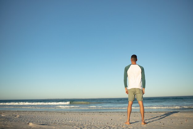 Hombre estar de pie, en la playa