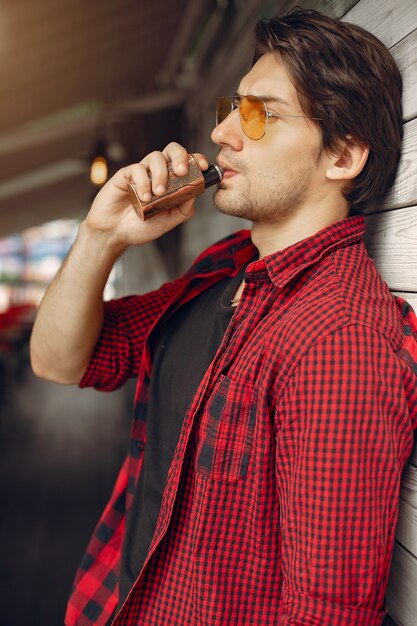 Hombre con estilo y elegante en una ciudad con vape