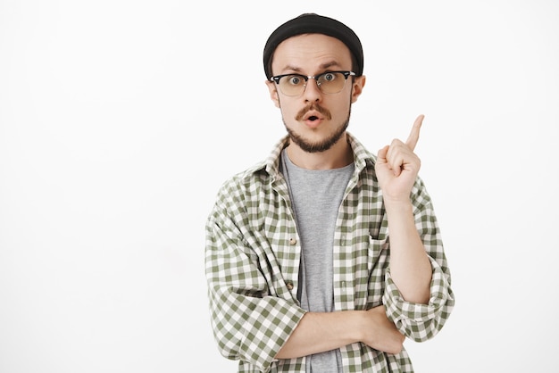 Hombre con estilo emocionado y divertido en gorro negro y gafas levantando el dedo índice en gesto eureka