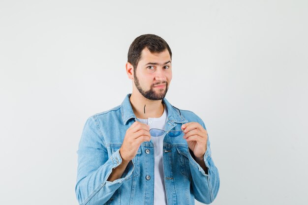 Hombre de estilo retro con chaqueta, camiseta con gafas de sol, vista frontal.