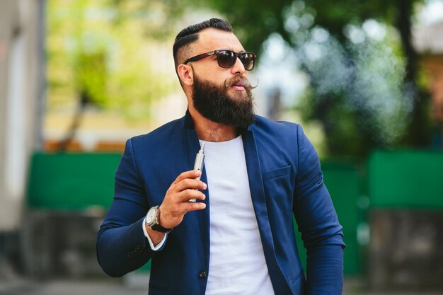 Hombre estiloso con gafas de sol y cigarro electrónico