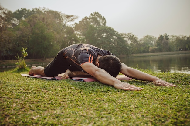 Foto gratuita hombre estirando el cuerpo al lado del lago