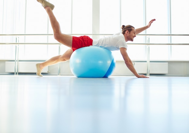 Hombre estirando con una pelota de yoga