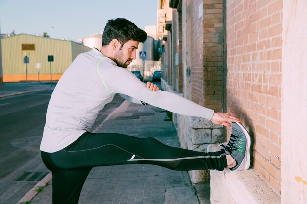 Hombre estirando las piernas en la calle