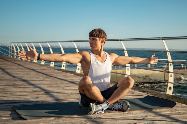 Hombre estirando sus brazos en la playa.