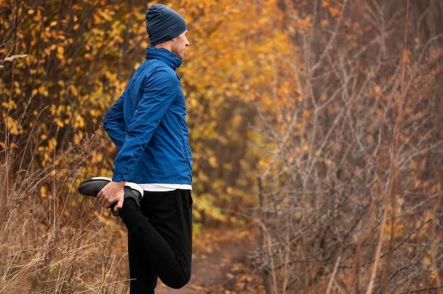 Foto gratuita hombre estirando sus piernas en el bosque