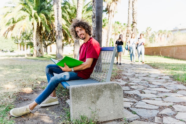 Hombre estudiando sentado en el banco al aire libre