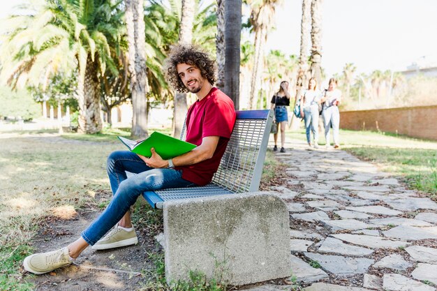 Hombre estudiando sentado en el banco al aire libre