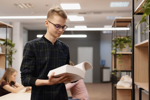 Un hombre estudiante recogiendo libros del estante