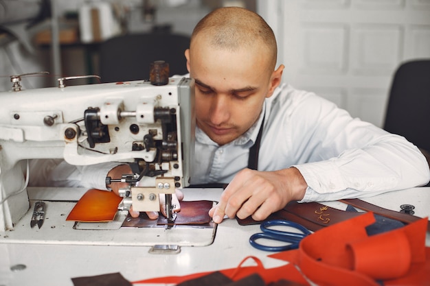 Foto gratuita el hombre en un estudio crea artículos de cuero.