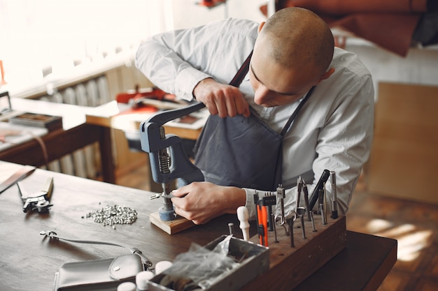 Foto gratuita el hombre en un estudio crea artículos de cuero.