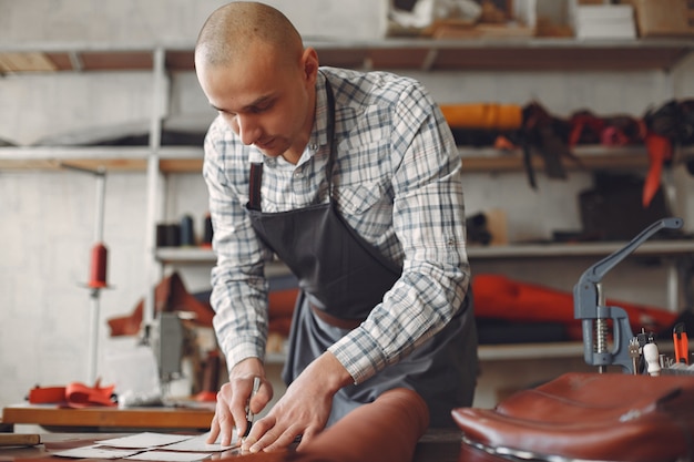 Foto gratuita el hombre en un estudio crea artículos de cuero.