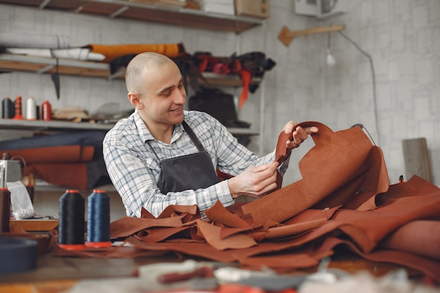 Foto gratuita el hombre en un estudio crea artículos de cuero.