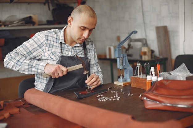 Foto gratuita el hombre en un estudio crea artículos de cuero.