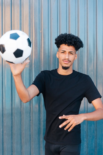 Hombre étnico lanzando fútbol a la cámara