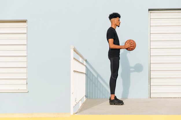 Hombre étnico moderno con baloncesto en la calle