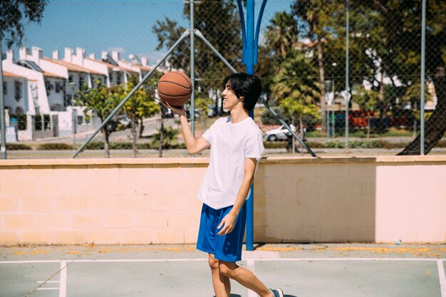 Hombre étnico sosteniendo baloncesto mientras está de pie en el patio