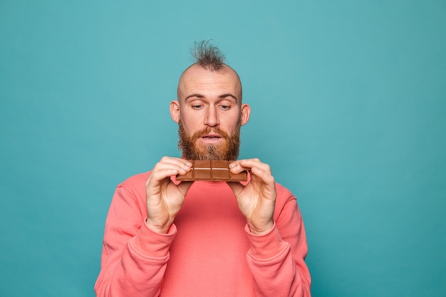 Hombre europeo barbudo en melocotón casual aislado, sosteniendo delicioso chocolate