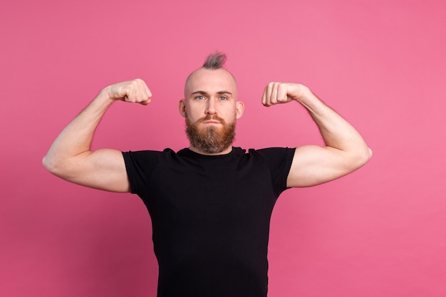 Hombre europeo fuerte sobre fondo rosa mostrando los músculos