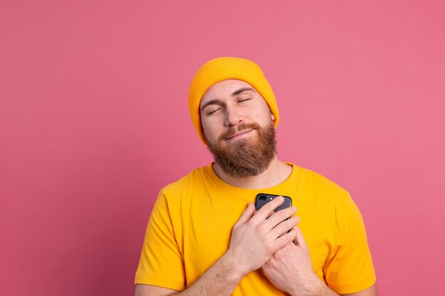 El hombre europeo recibió un mensaje encantador, sosteniendo el teléfono móvil sonriendo en rosa