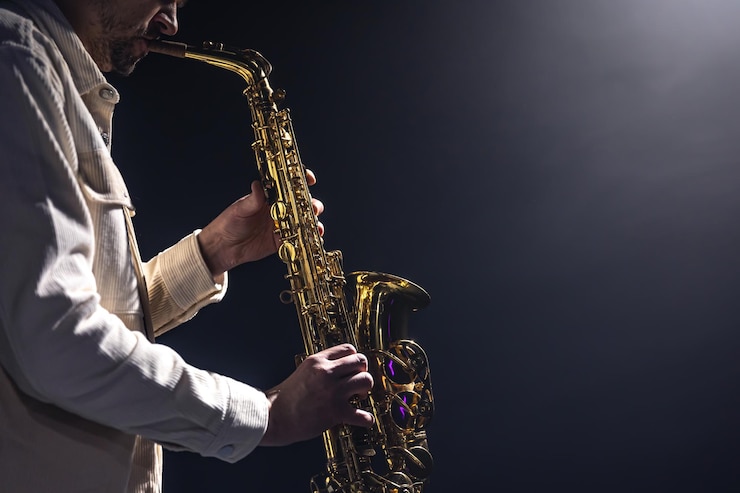 Foto gratuito un hombre europeo toca el saxofón en la oscuridad.