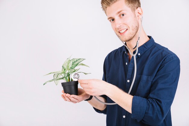 Hombre examinando planta en maceta con estetoscopio