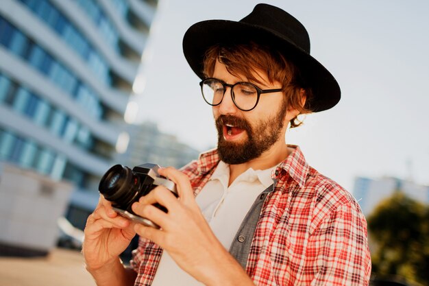 Hombre excitado con barba con cámara de película retro interesante, haciendo fotos