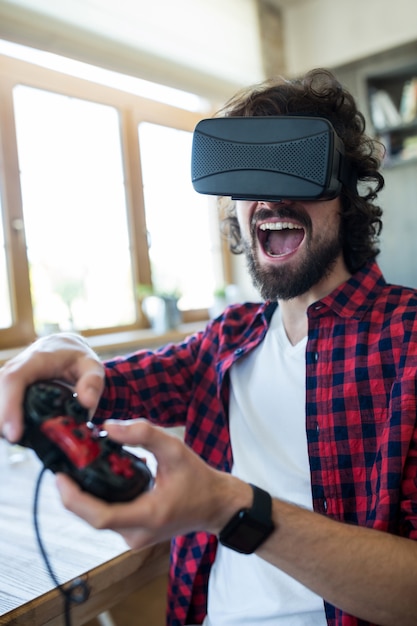 Foto gratuita hombre excitado usando casco de realidad virtual y jugar con videojuegos