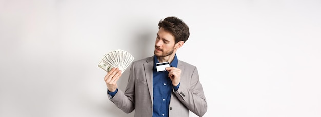 Hombre exitoso mostrando tarjeta de crédito de plástico y mirando billetes de dólar ventilador haciendo depósito de dinero stan