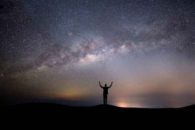 Hombre exitoso silueta en la cima de la colina sobre un fondo con estrellas