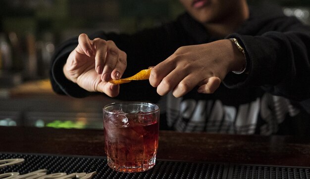 Hombre exprimiendo un limón en su whisky en un bar.