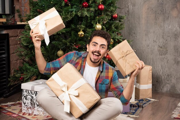 Hombre feliz agitando sus regalos para entender lo que hay dentro.